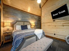 Un dormitorio acogedor con cama, lámparas de noche, un banco y televisión montada.