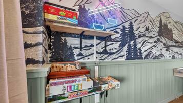 A wall with a mountain-themed mural and shelves holding board games.
