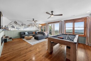 Ein Raum mit Billardtisch, einer Couch, einem Deckenventilator und einem Wandbild einer Berglandschaft.