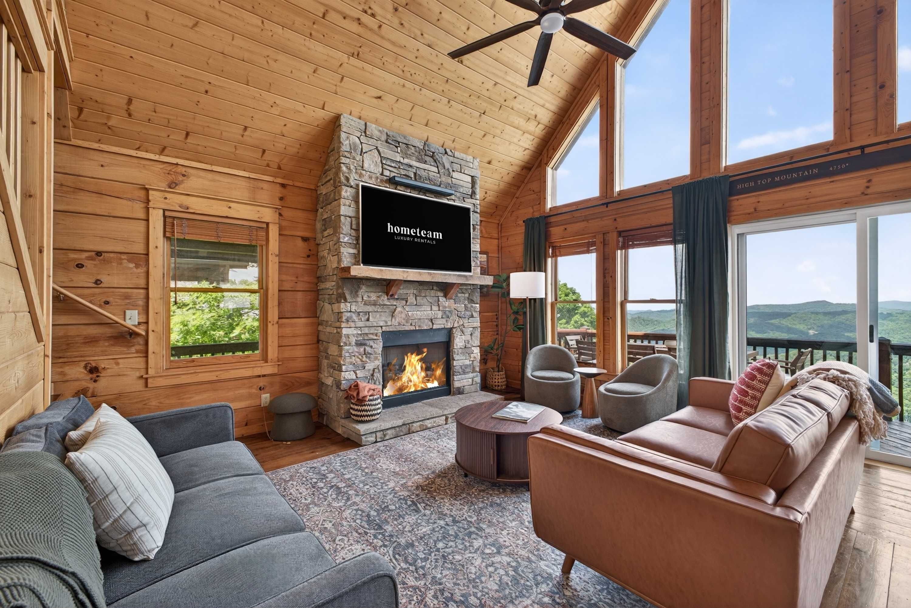 A cozy interior with a stone fireplace, a sofa, a chair, and a view of the outdoors.