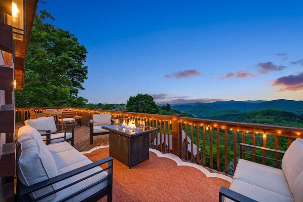 Eine Terrass mit Feuerstelle, Sitzgelegenheiten und Blick auf die Berge.