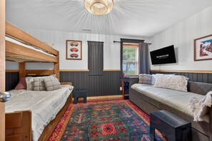A bedroom with bunk beds, a sofa, a television, and a patterned rug. - Mins to Hatley Pointe Hot Tub Views Sauna (Mars Hill)