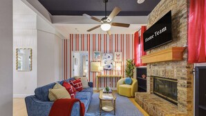 Ein Wohnzimmer mit einem blauen Sofa, einem Kamin, einem Fernseher und einer gestreiften Wand.