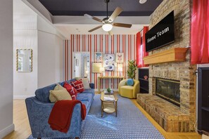A living room with a blue sofa, a fireplace, a television, and a striped wall. - Sleeps 10 Heated Pool Game Room Hot Tub (Largo)