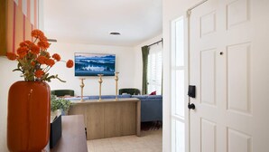 A room with a wooden desk, a vase with flowers, a painting on the wall, and a door. - Starcrest 4 Br Haven Pool Hot Tub Putt Putt Arcade (San Antonio)
