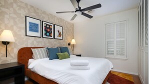 A bedroom with a bed, two bedside tables, a ceiling fan, and wall-mounted lamps. - Starcrest 4 Br Haven Pool Hot Tub Putt Putt Arcade (San Antonio)