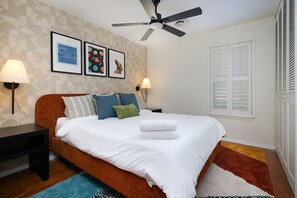 Ein Schlafzimmer mit einem Bett, zwei Nachttischen, einem Deckenventilator und Wandleuchten.