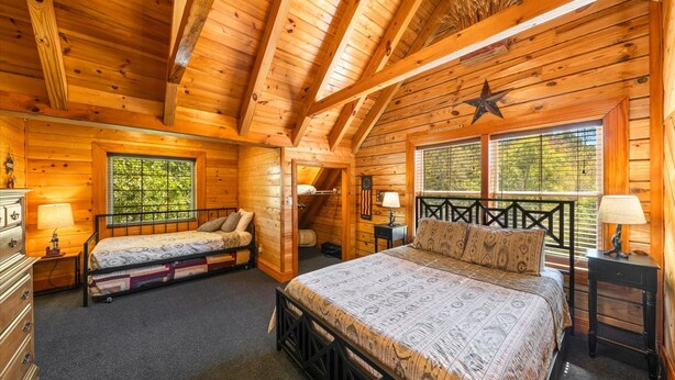 A cabin with two beds, a star decoration, and a window with a view of trees. - Luxury 8BR Mountain Lodge Hot Tub Fire Pit (Byrdstown)