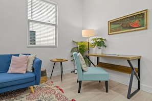 Ein Wohnzimmer mit einem blauen Sofa, einem hellblauen Sessel, einem Holztisch, einer Stehlampe und einem Bild von einem Alligator.