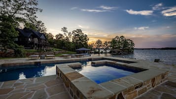 A swimming pool with stone borders, a wooden deck, and lounge chairs.