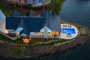 Een groot huis met zwembad, stenen gevel en uitzicht op het water.