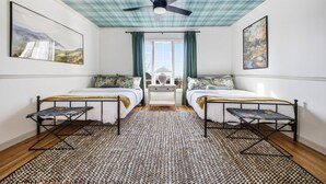 A room with two beds, a ceiling fan, and artwork on the walls. - Luxury Mtn Retreat Hot Tub Sleeps 18 Game Room (Asheville)