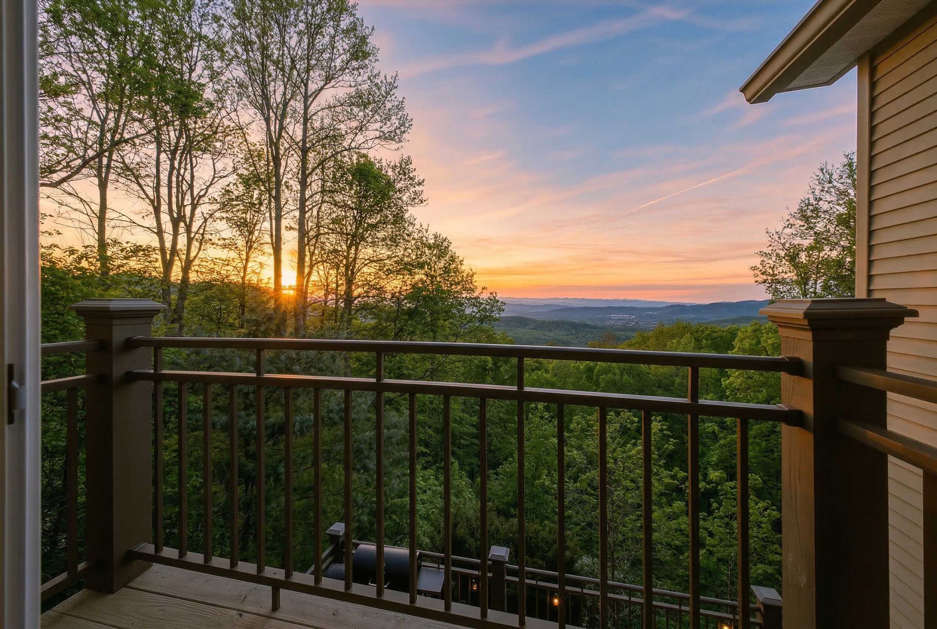 A balcony with a view of trees and a sunset.