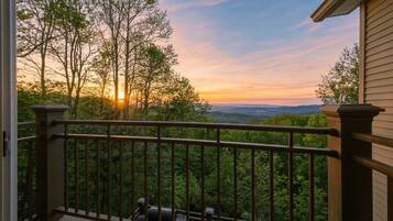 A balcony with a view of trees and a sunset.