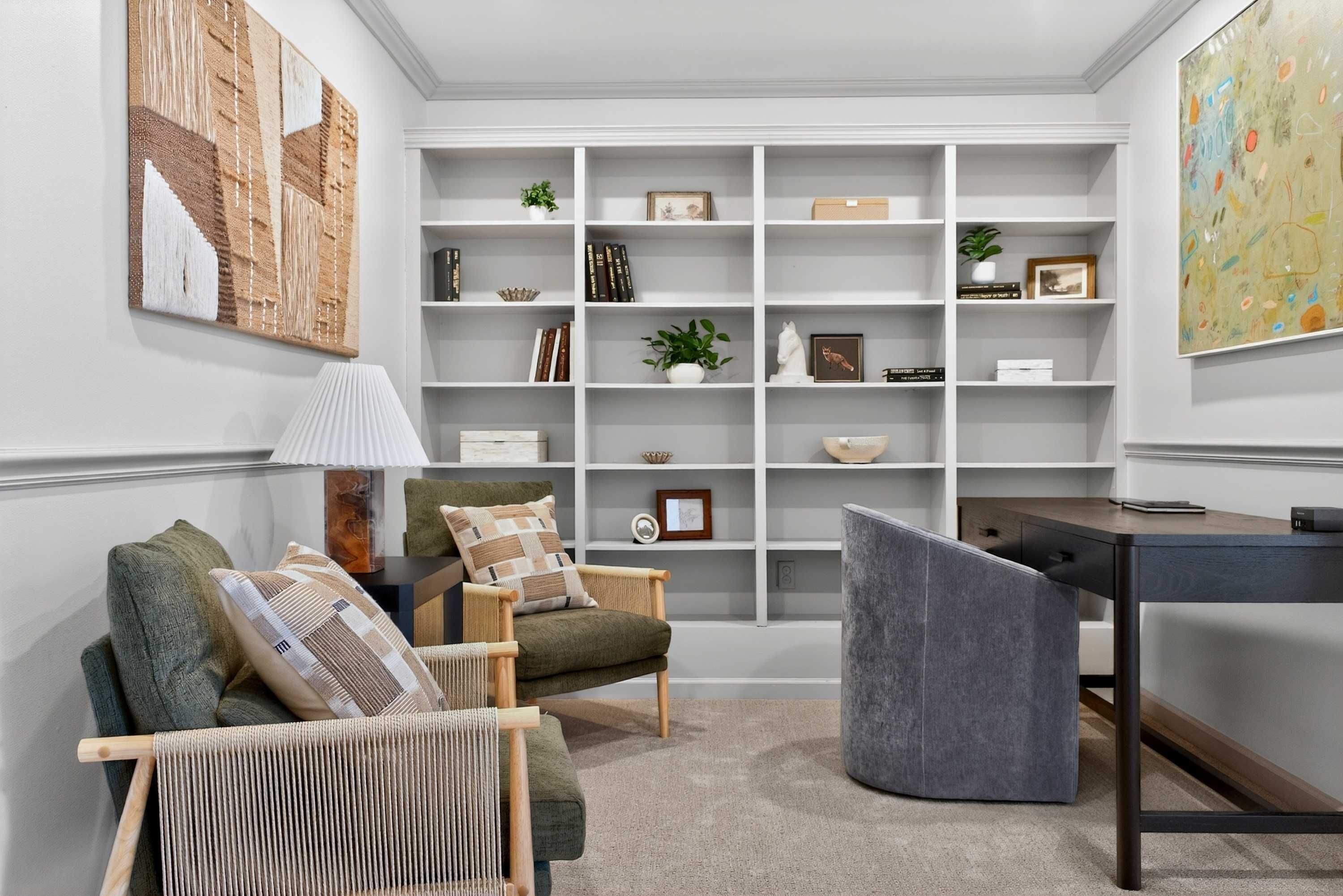 A modern living room with a bookshelf, a desk, and a comfortable seating area.