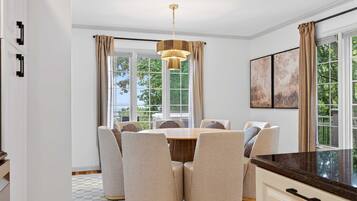 A dining area with a round table, six chairs, and a hanging light fixture.