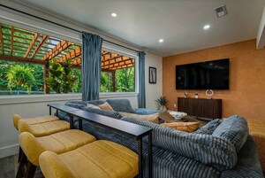 Una sala de estar moderna con un conjunto de sofás, una mesa de comedor y un televisor montado en la pared.