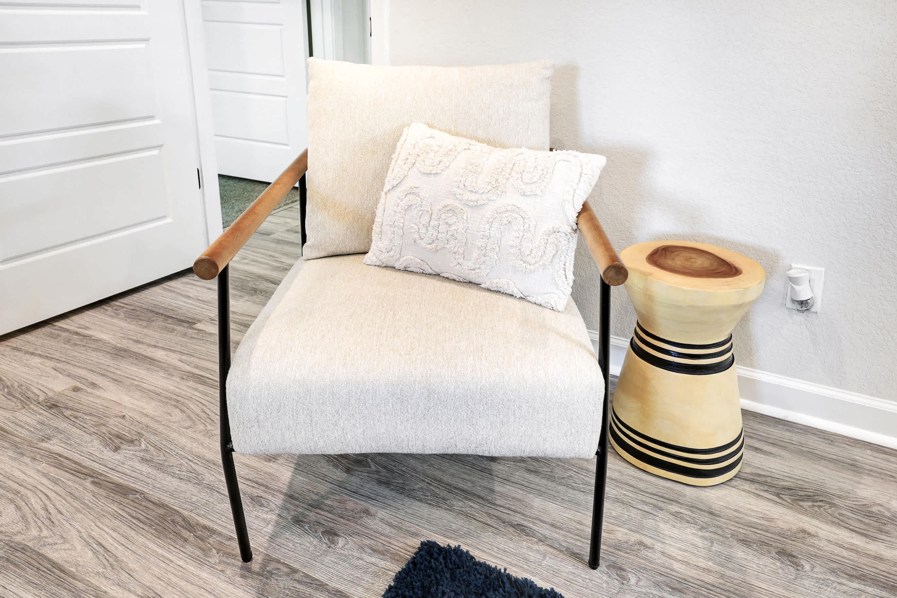 Una silla con cojín y un taburete de madera con rayas.