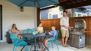Un patio con tavolo e sedie, un barbecue e un recinto in legno.