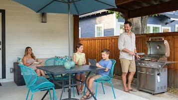 En terrasse med et bord, stole, grill og et træhegn.
