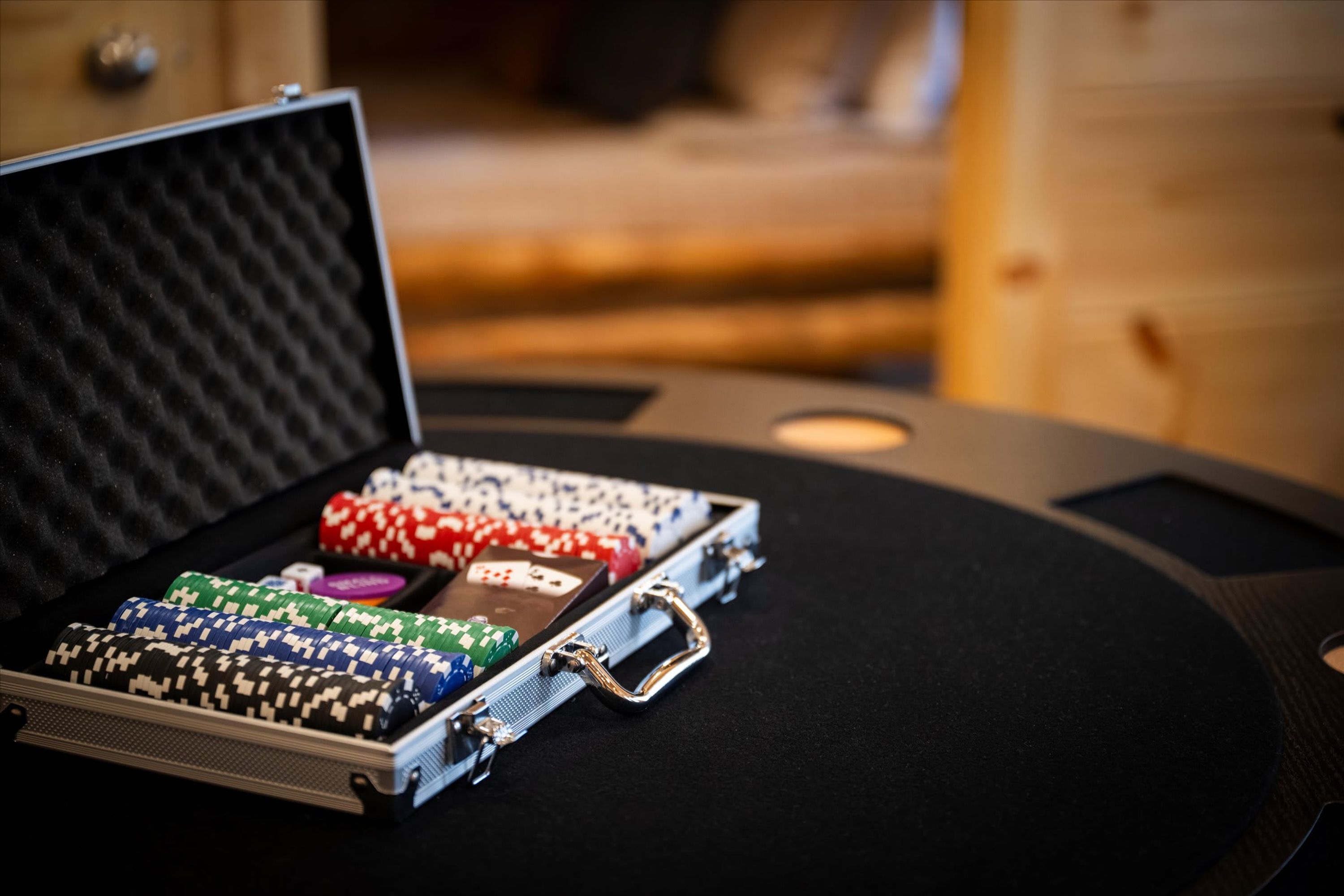 En pokerchip-organisator med diverse chips og et kortspil på et bord.