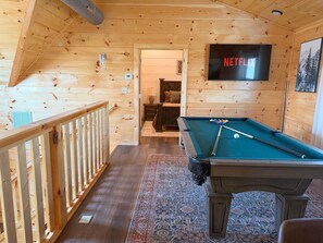 A wooden interior with a pool table, a Netflix sign, and a cozy seating area. - Smoky Mtn Retreat Sauna Hot Tub Game Room (Pigeon Forge)