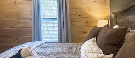 A wooden-paneled room with a bed, a window with curtains, and a headboard.