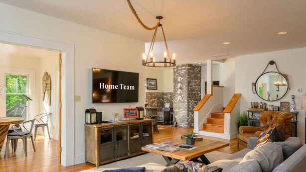 A modern living room with a TV, sofa, coffee table, and a staircase leading to another level. - Mountain Views Hot Tub Firepit Game Room (Asheville)