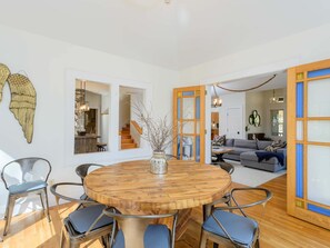 A dining area with a round wooden table, six chairs, and a vase with branches. - Mountain Views Hot Tub Firepit Game Room (Asheville)