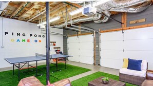 A ping pong table, seating area, and a wall with 'PING PONG GAME ON' text. - Mountain Views Hot Tub Firepit Game Room (Asheville)