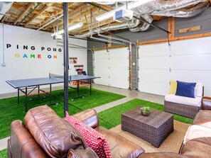 A ping pong table, seating area, and a wall with 'PING PONG GAME ON' text. - Mountain Views Hot Tub Firepit Game Room (Asheville)