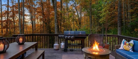 Terraza al aire libre con un hogar a fuego de piedra, una parrilla y asientos.