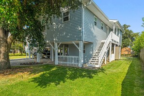 A two-story house with a covered porch and a staircase leading to the second floor. - Waterfront Firepit Golfcart Mins to Casino Beach (Bay St Louis)