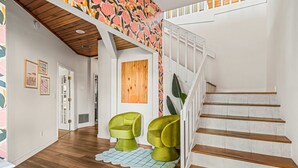 Eine Treppe mit Holzbodenstufen und weißen Geländern, die zu einer Zwischenebene mit floralem Wanddesign führt.