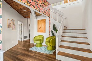 Eine Treppe mit Holzbodenstufen und weißen Geländern, die zu einer Zwischenebene mit floralem Wanddesign führt.