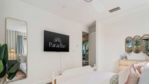 Ein Hotelzimmer mit Bett, Fernseher zeigt 'Paradiso', Spiegel und Kommode.