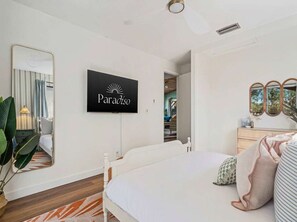 Ein Hotelzimmer mit Bett, Fernseher zeigt 'Paradiso', Spiegel und Kommode.