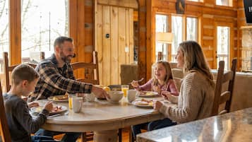 A family dining in a wooden cabin with a round table and chairs.