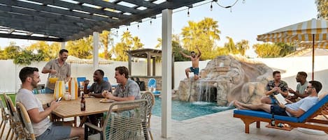 Un patio al aire libre con piscina, mesa de comedor y sillones de descanso.