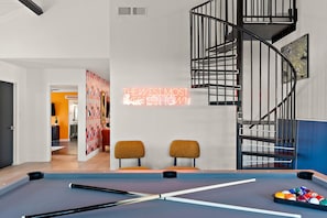 A modern interior with a pool table, two chairs, a neon sign, and a spiral staircase. - The Desert Daydream Heated Pool Water Slide (Scottsdale)