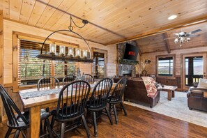 A wooden interior with a dining area, fireplace, and a flat-screen TV displaying 'NETFLIX'. - Family-friendly Cabin Hot Tub Games Views (Morganton)