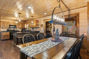 Interior de una cabaña de madera con cocina, comedor y un árbol de Navidad.