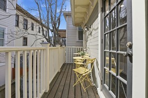 A wooden deck with a table and chairs, a white railing, and a door with a window. - Charming Savannah Getaway Hot Tub Sleeps 8 (Savannah)