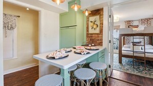 A compact kitchen with a central island, a dining area with four chairs, and a bunk bed in the adjacent room. - Charming Savannah Getaway Hot Tub Sleeps 8 (Savannah)