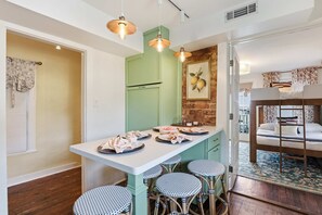 A compact kitchen with a central island, a dining area with four chairs, and a bunk bed in the adjacent room. - Charming Savannah Getaway Hot Tub Sleeps 8 (Savannah)