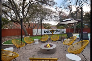 An outdoor seating area with yellow chairs, a fire pit, and a sign reading 'SAN ANTONIO'. - Giddy Up Getaway Pool Hot Tub Family Fun (San Antonio)