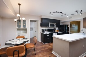 A modern kitchen with a central island, black cabinets, a microwave, and a coffee maker. - Giddy Up Getaway Pool Hot Tub Family Fun (San Antonio)