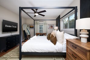 A four-poster bed with white bedding, a ceiling fan, and a television on the wall. - Giddy Up Getaway Pool Hot Tub Family Fun (San Antonio)