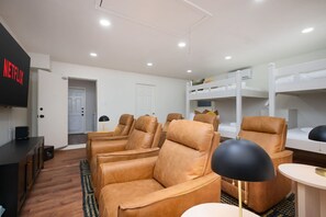 A room with a TV, leather chairs, bunk beds, and a small table. - Giddy Up Getaway Pool Hot Tub Family Fun (San Antonio)