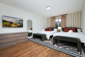 A hotel room with two beds, a wooden dresser, a large mirror, a painting on the wall, and a patterned rug. - The Hacienda Pool Hot Tub Games More (San Antonio)